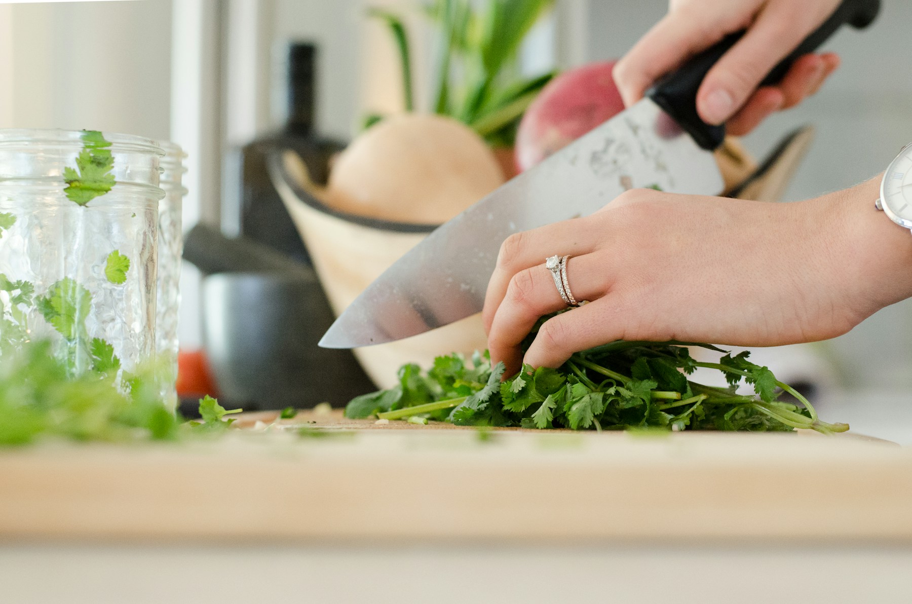 Hands chopping fresh herbs on a kitchen board