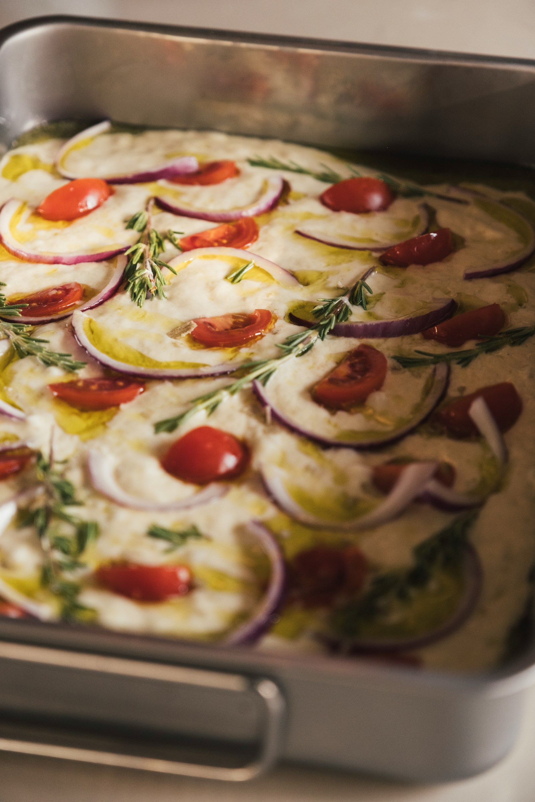 Golden focaccia baked with tomatoes, onion, and rosemary