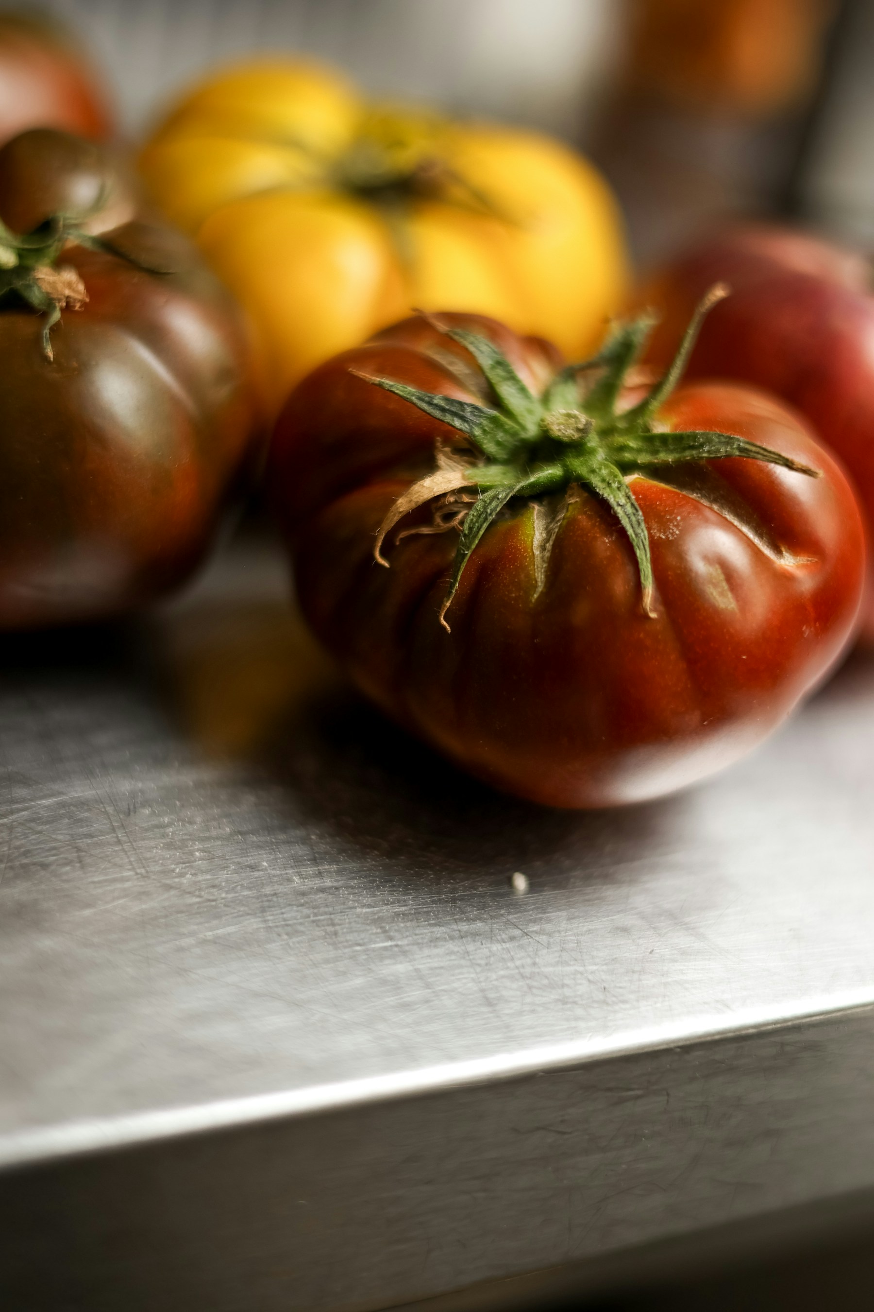 A dark red heirloom tomato on a metal surface