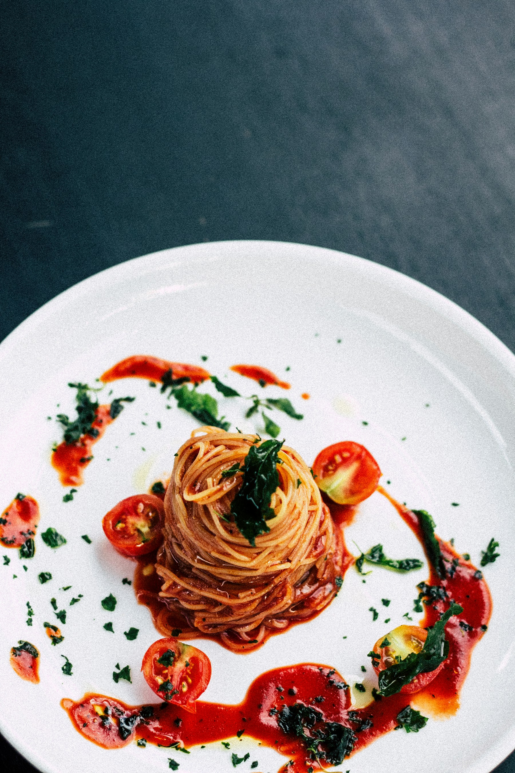 Tomato pasta finished with basil in a shallow white bowl
